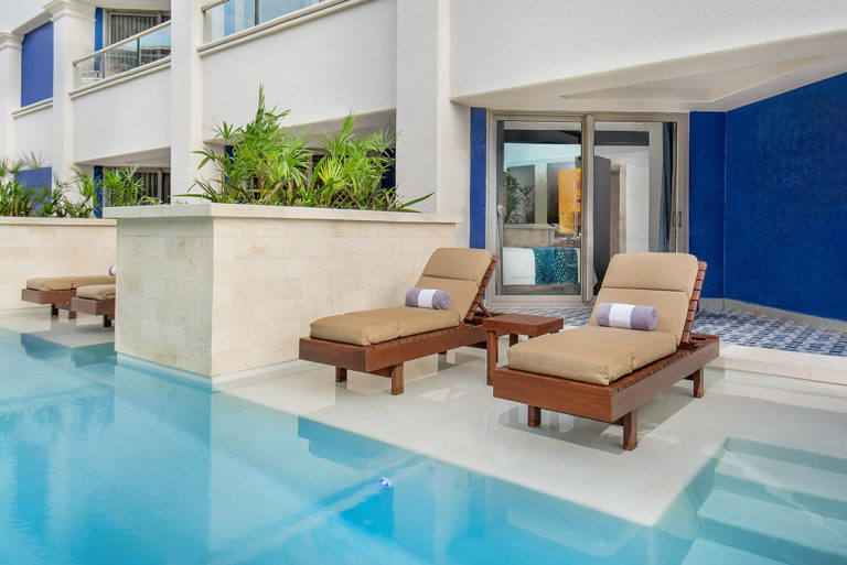 A private swim up pool with lounge chairs attached to a suite.
