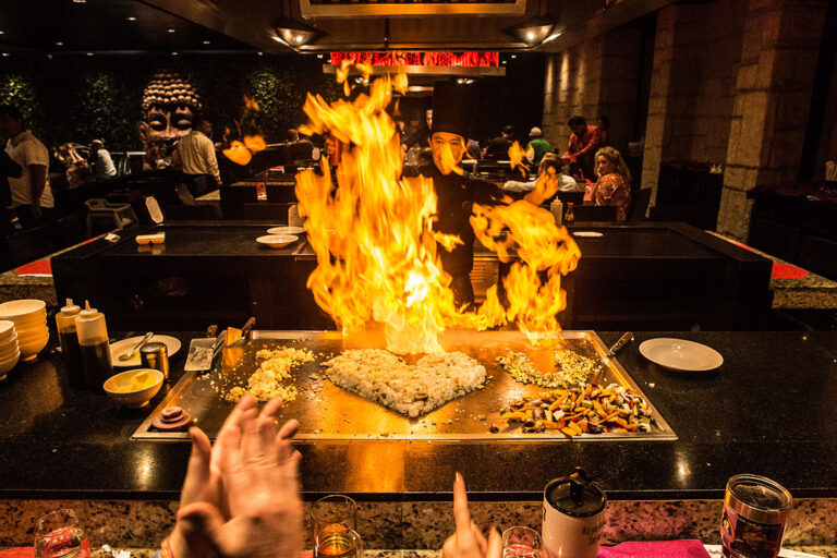 A hibachi table with fire lighting up the area.