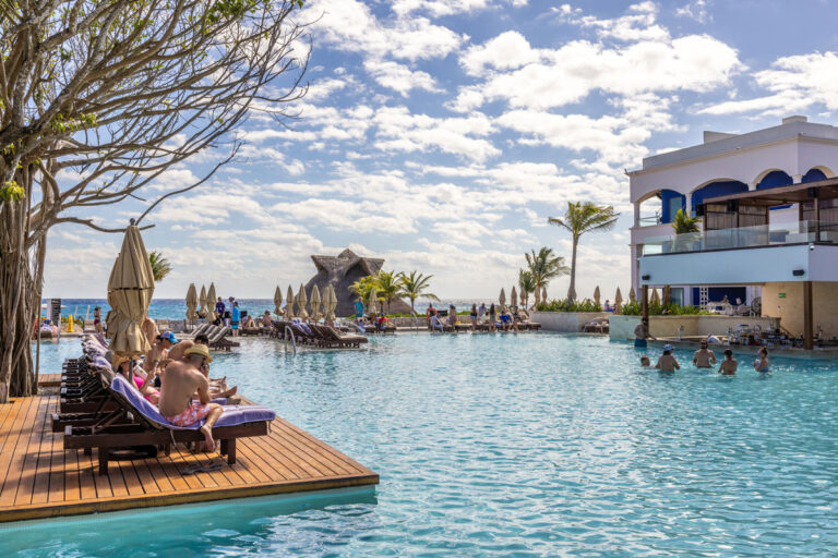 Guests sitting on pool chairs next to a pool.