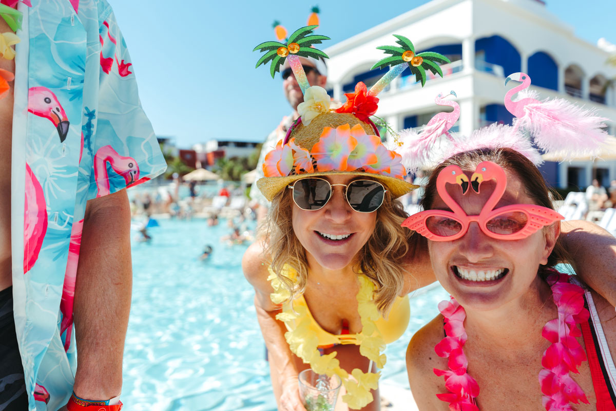 A photo of guests wearing tropical glasses by the pool.