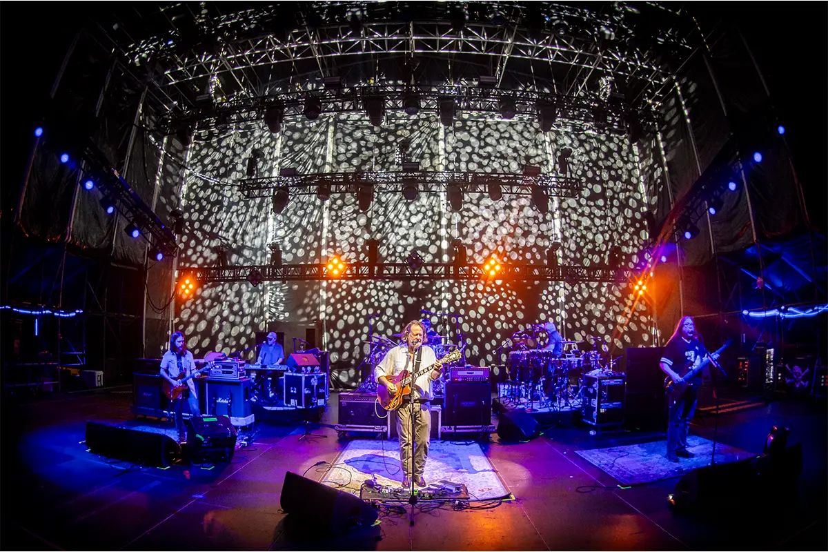 Close up photo of JB from Widespread Panic performing on the Main Stage with lights shining on him.