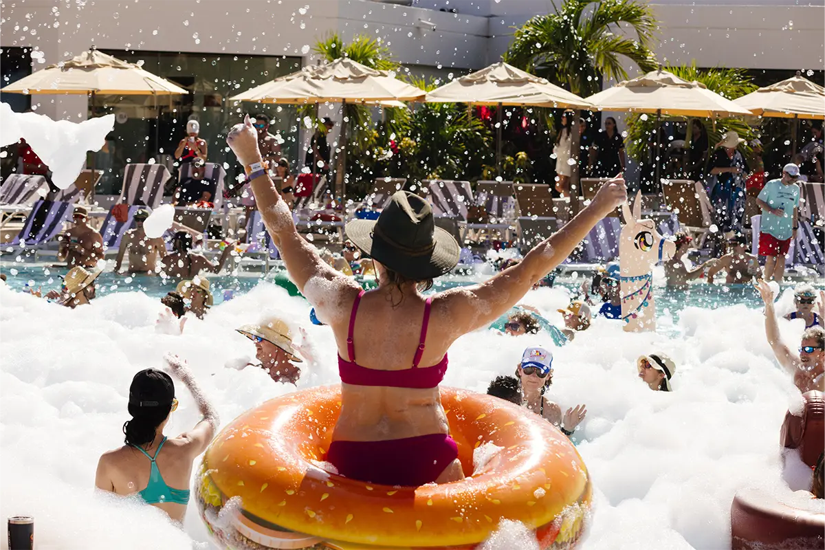 A guest with their hands up in the pool during a foam party.